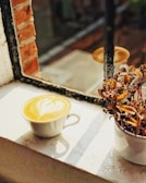 A sunlit morning coffee scene by a window with a small potted plant.