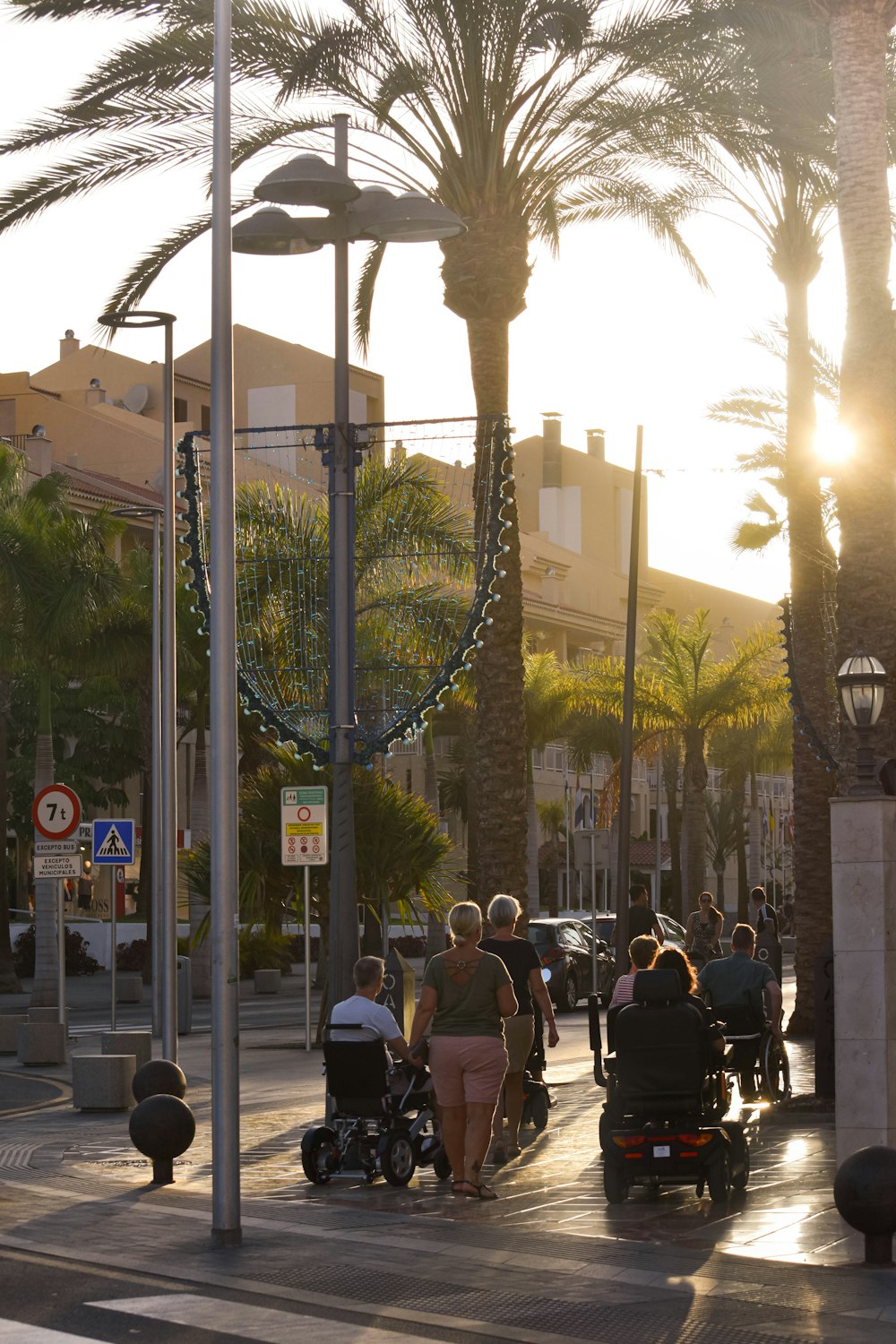 Palmbomen en lopende mensen op straat tijdens de zonsondergang