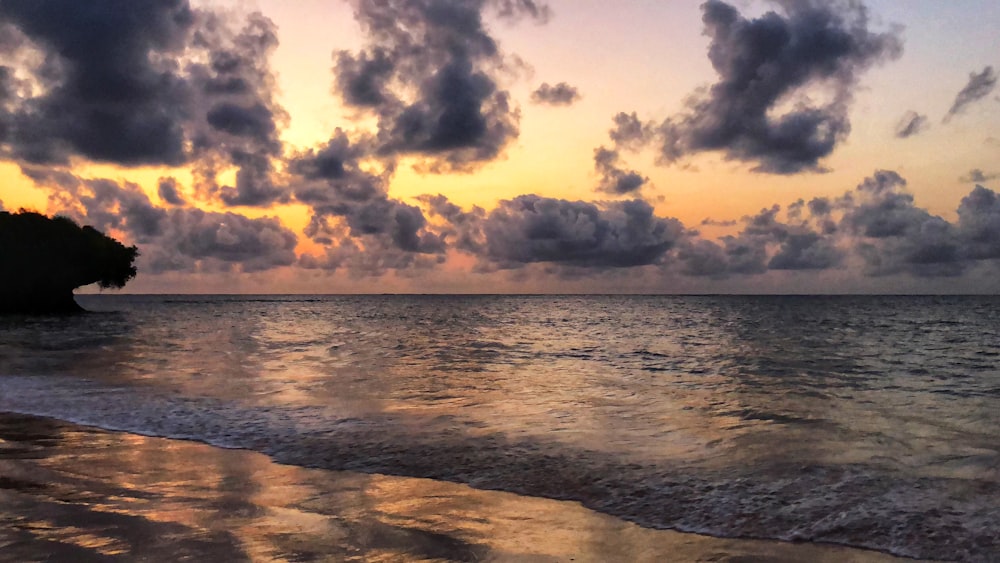 body of water under white sky at golden hour