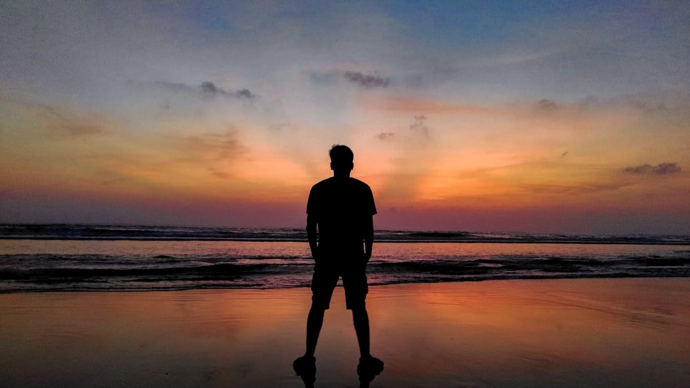 person standing on shore during golden hour