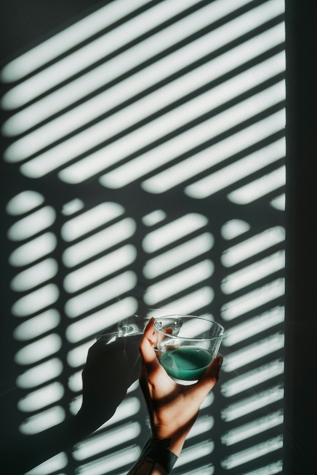 person holding drinking glass cup with green liquid