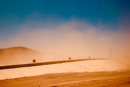 A worker removing dust and debris from the ground in a desert setting.