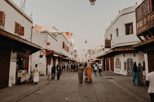 a group of people walking down a street next to tall buildings