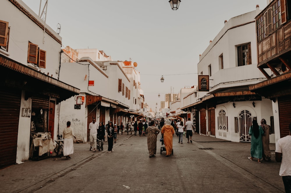 a group of people walking down a street next to tall buildings