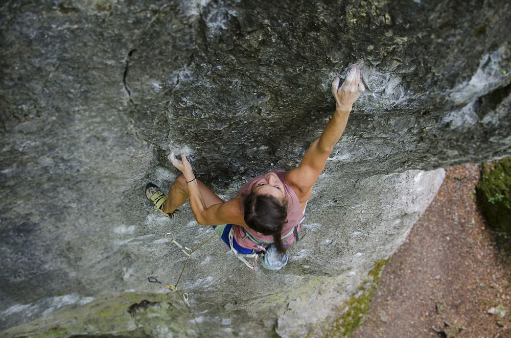 woman wearing pink tank top climbing on stone