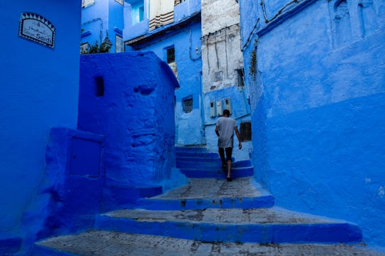 man walking up staircase between blue concrete buildings in Chefchaouen Morocco