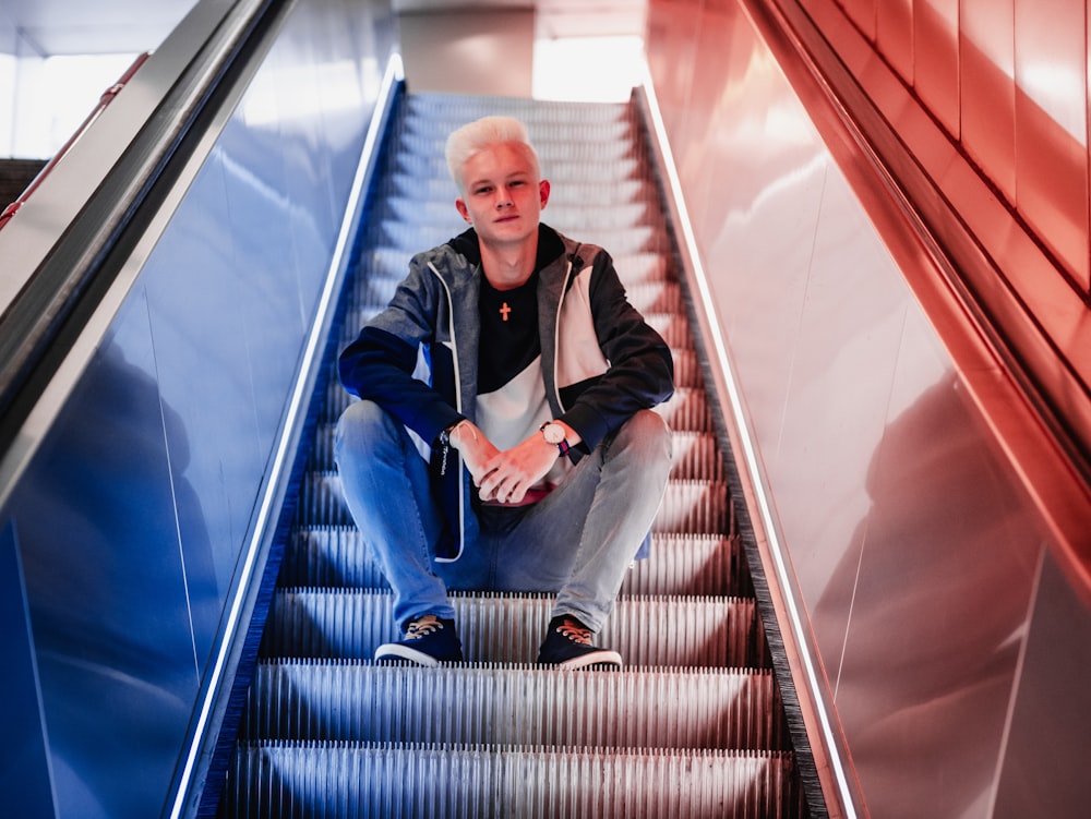 hombre sentado en la escalera mecánica