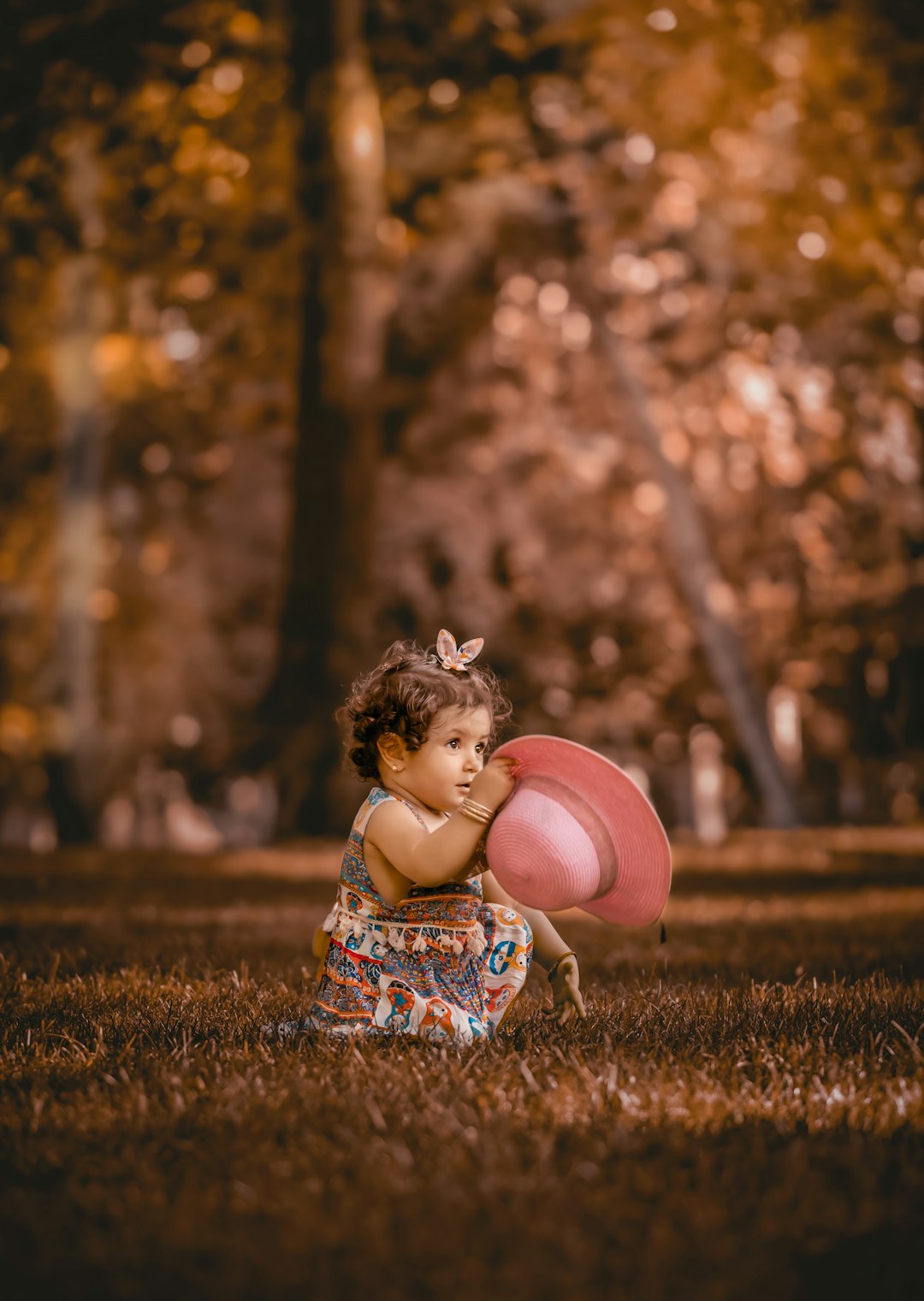 girl in blue and white dress sitting on grass near trees