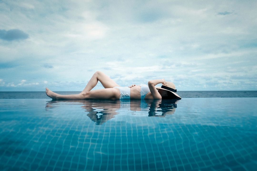 woman lying at the side of the pool during day