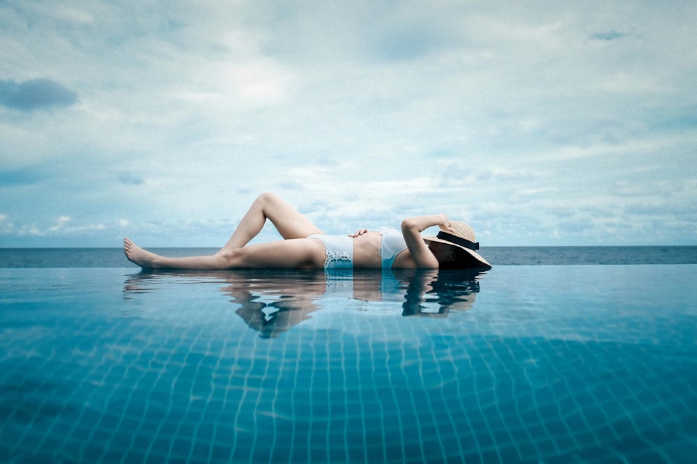 woman lying at the side of the pool during day