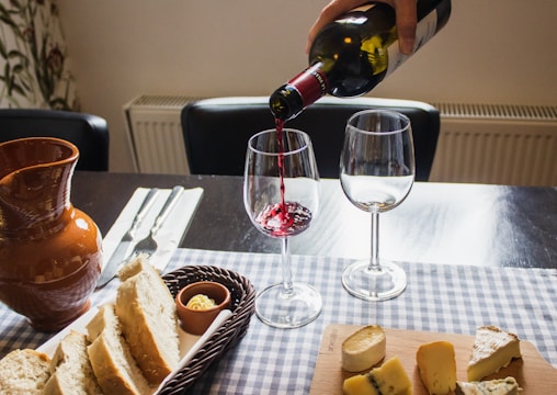 Close-up of a rustic table with Manchego cheese, a glass of red wine, and traditional bread.