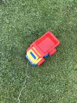 A smiling child pushing a Tonka fire truck across a grassy backyard.