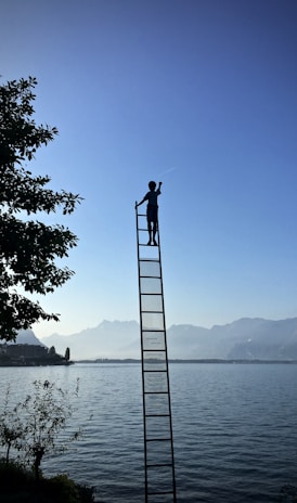 boy on ladder under blue sky