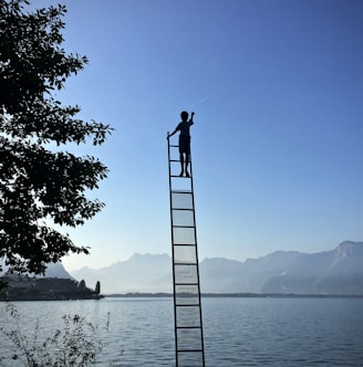 boy on ladder under blue sky
