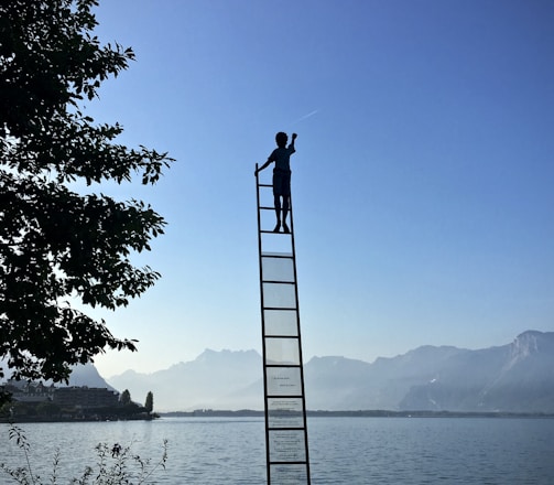 boy on ladder under blue sky