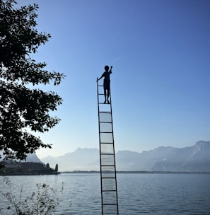 boy on ladder under blue sky