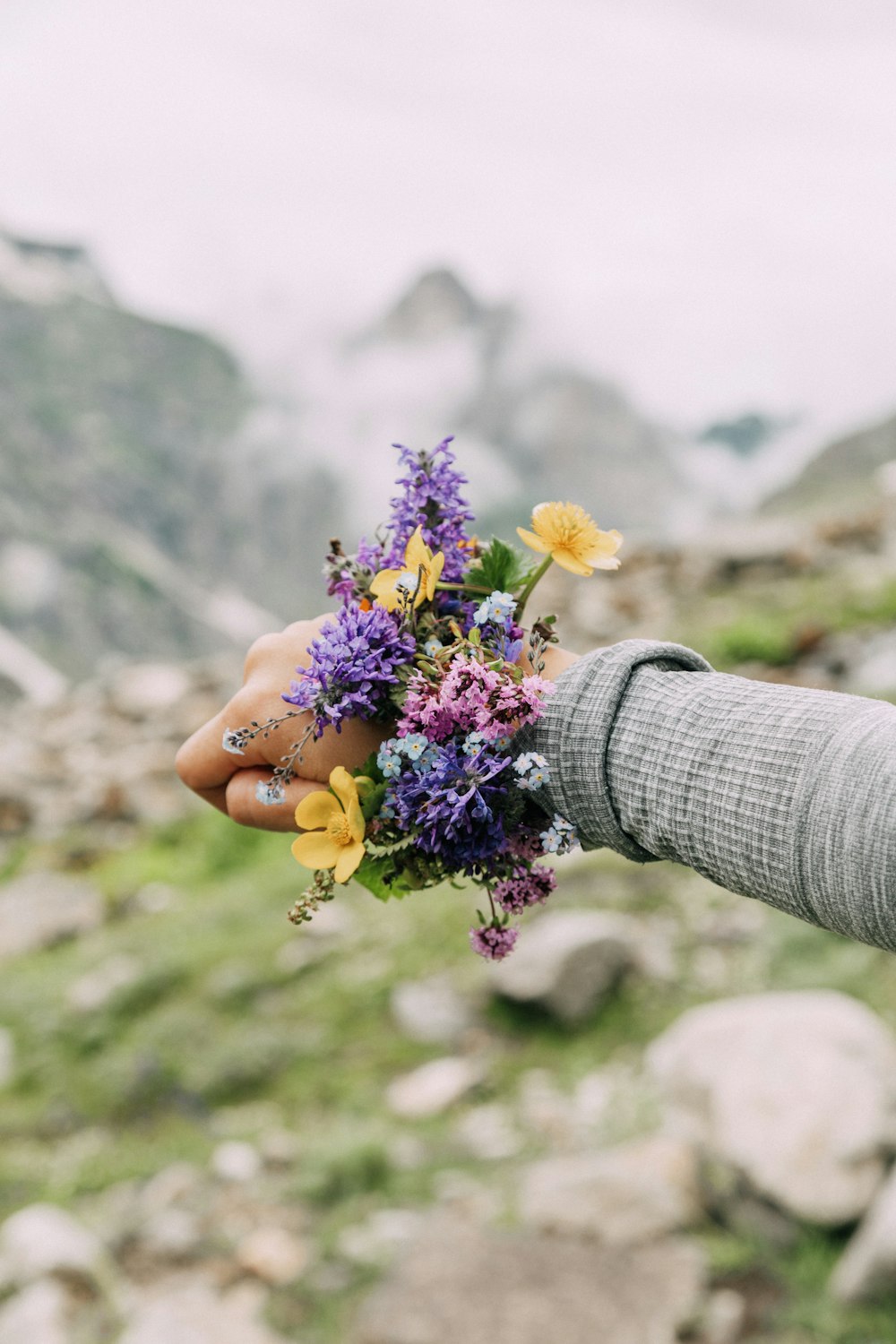 woman shows her purple and yellow flower bracelet on her wrist