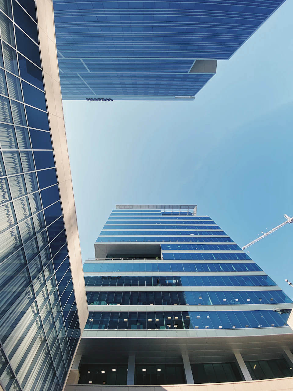 Tall glass and steel building with curved facade reflecting surrounding environment and cityscape