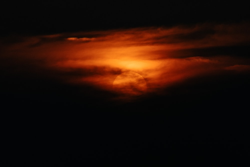 the sun is setting behind a cloud in the sky