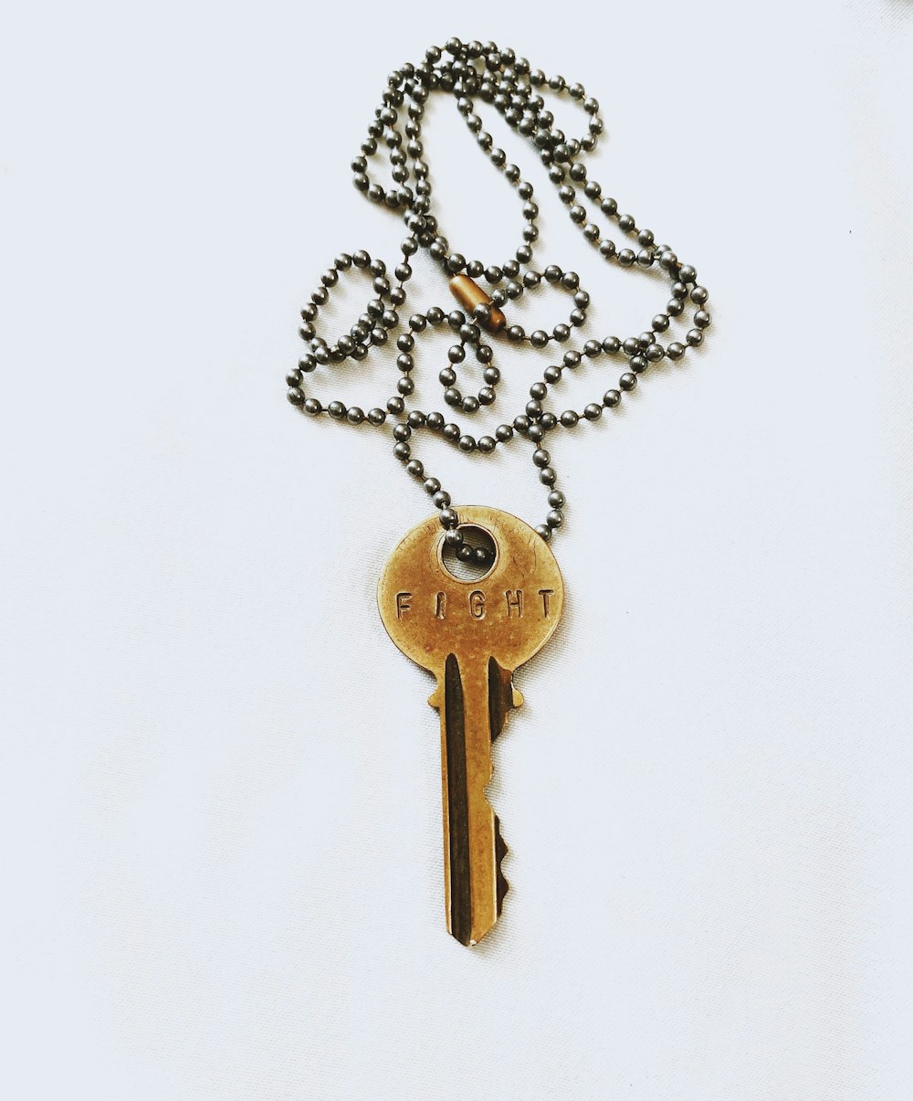 graue Schlüsselkampf-Anhänger-Halskette auf weißem Hintergrund
