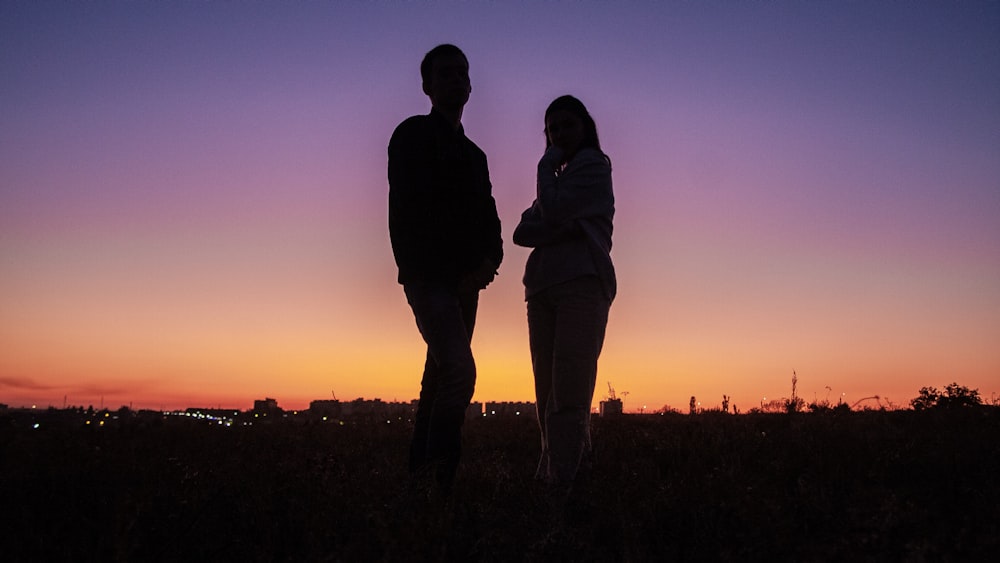 man and woman stand on green grass