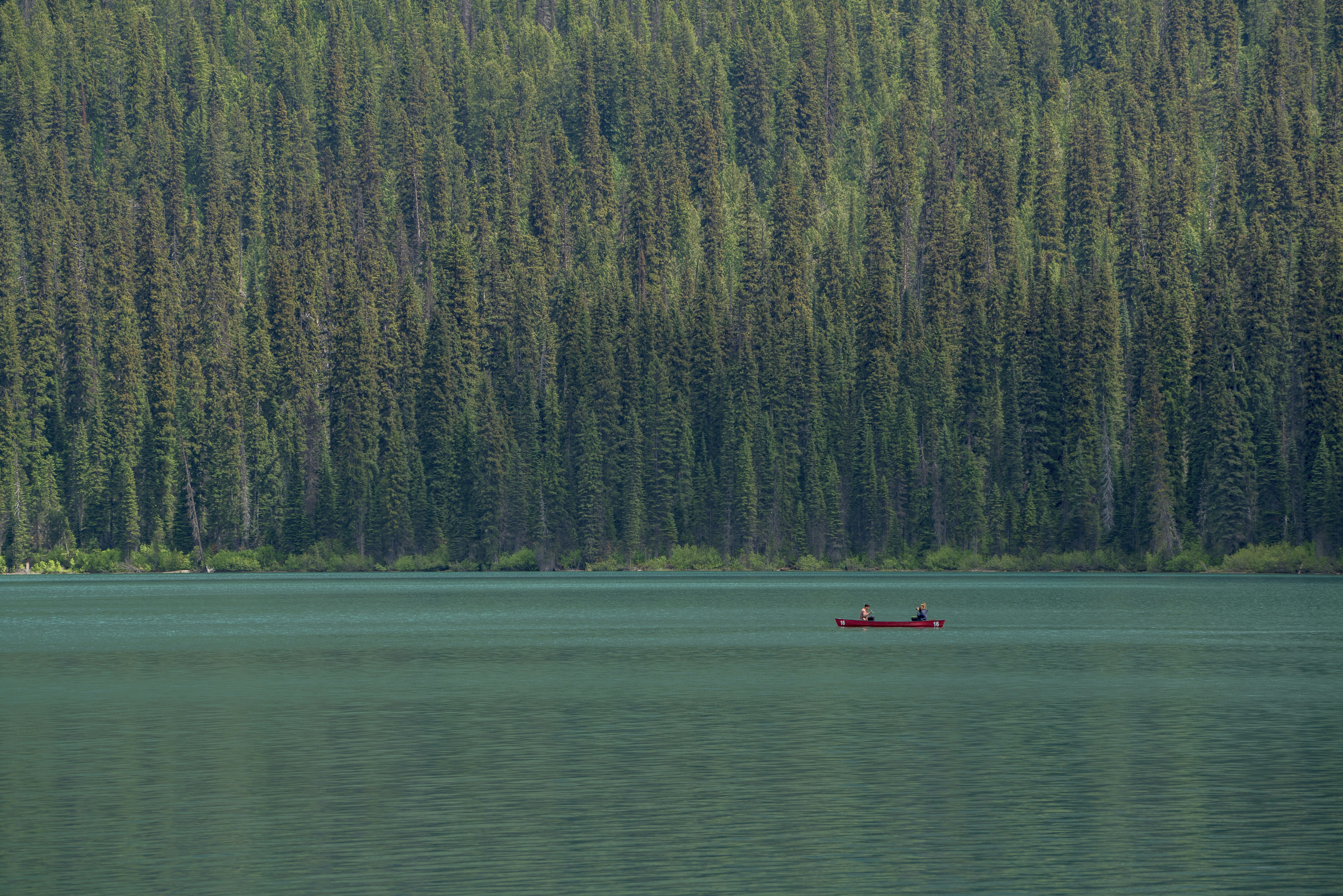 photo of people riding on red canoe boat onm lake