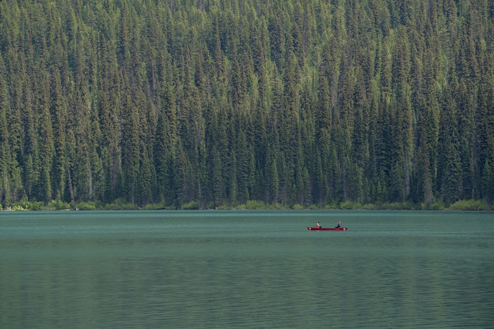 Foto de personas montadas en un bote de canoa roja en el lago