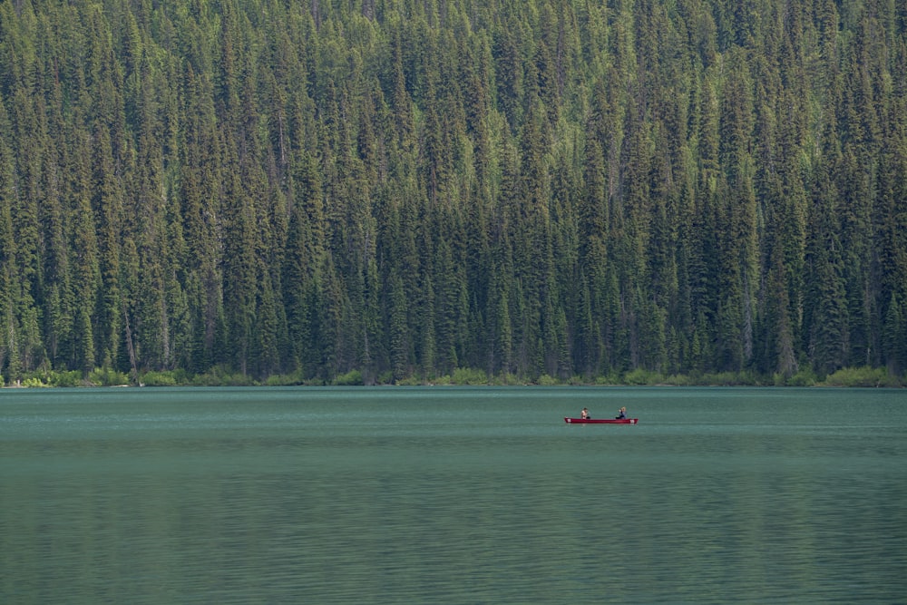 photo of people riding on red canoe boat onm lake