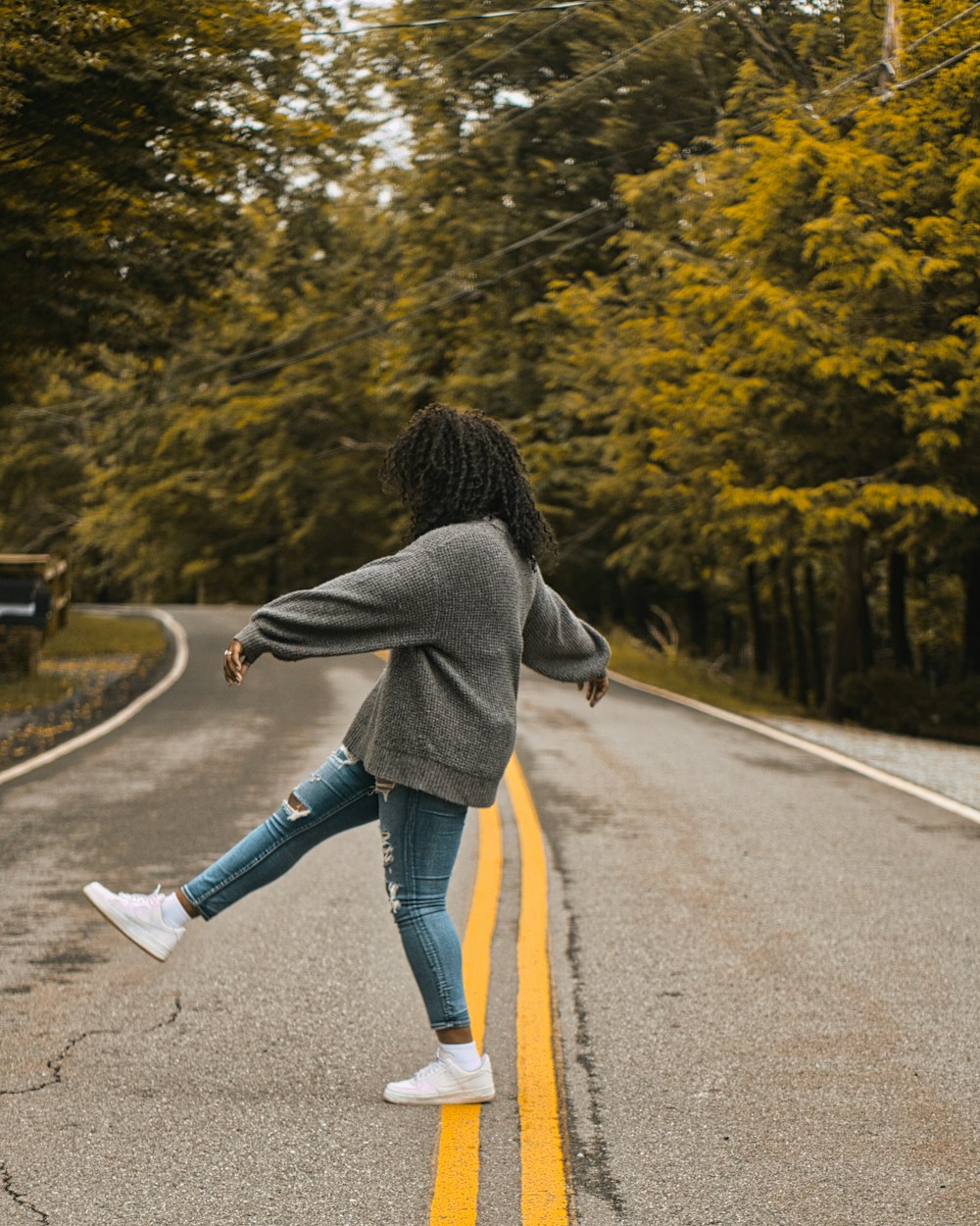 woman in gray jacket standing on road