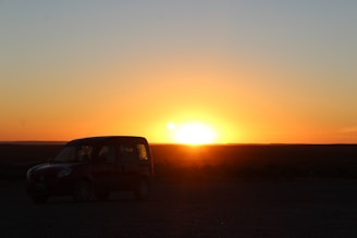 A car parked in a driveway with a sunset in the background.