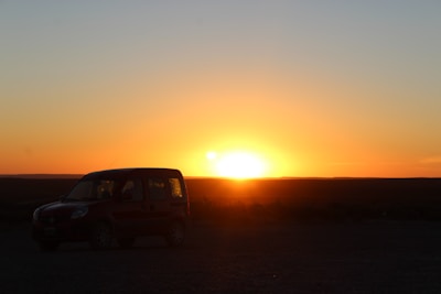 A car parked in a driveway with a sunset in the background.