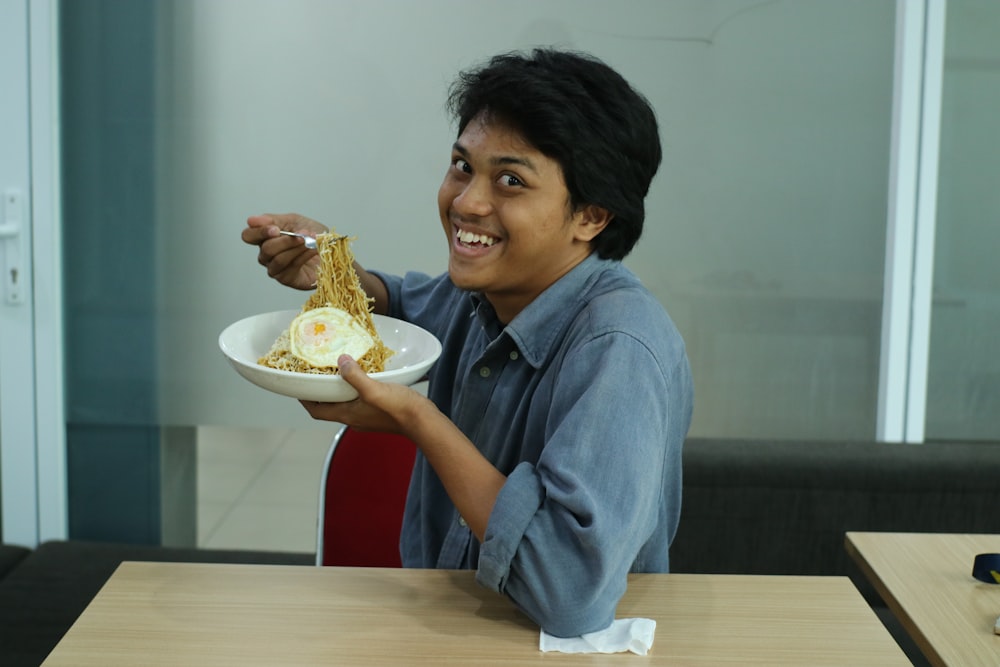 man wearing blue dress shirt holding round white bowl