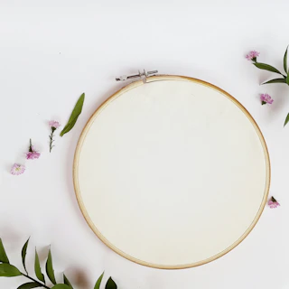 Close-up of a colorful embroidery hoop with floral patterns in progress on a wooden table.