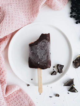 Rich chocolate ice cream melting slightly on a rustic wooden table