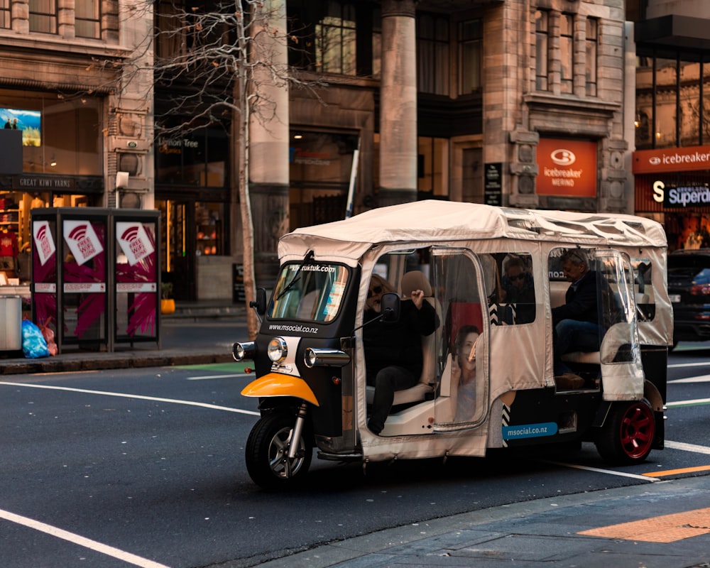 people riding autorickshaw on road near buildings