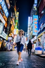 woman walking between buildings with lighted signs at night