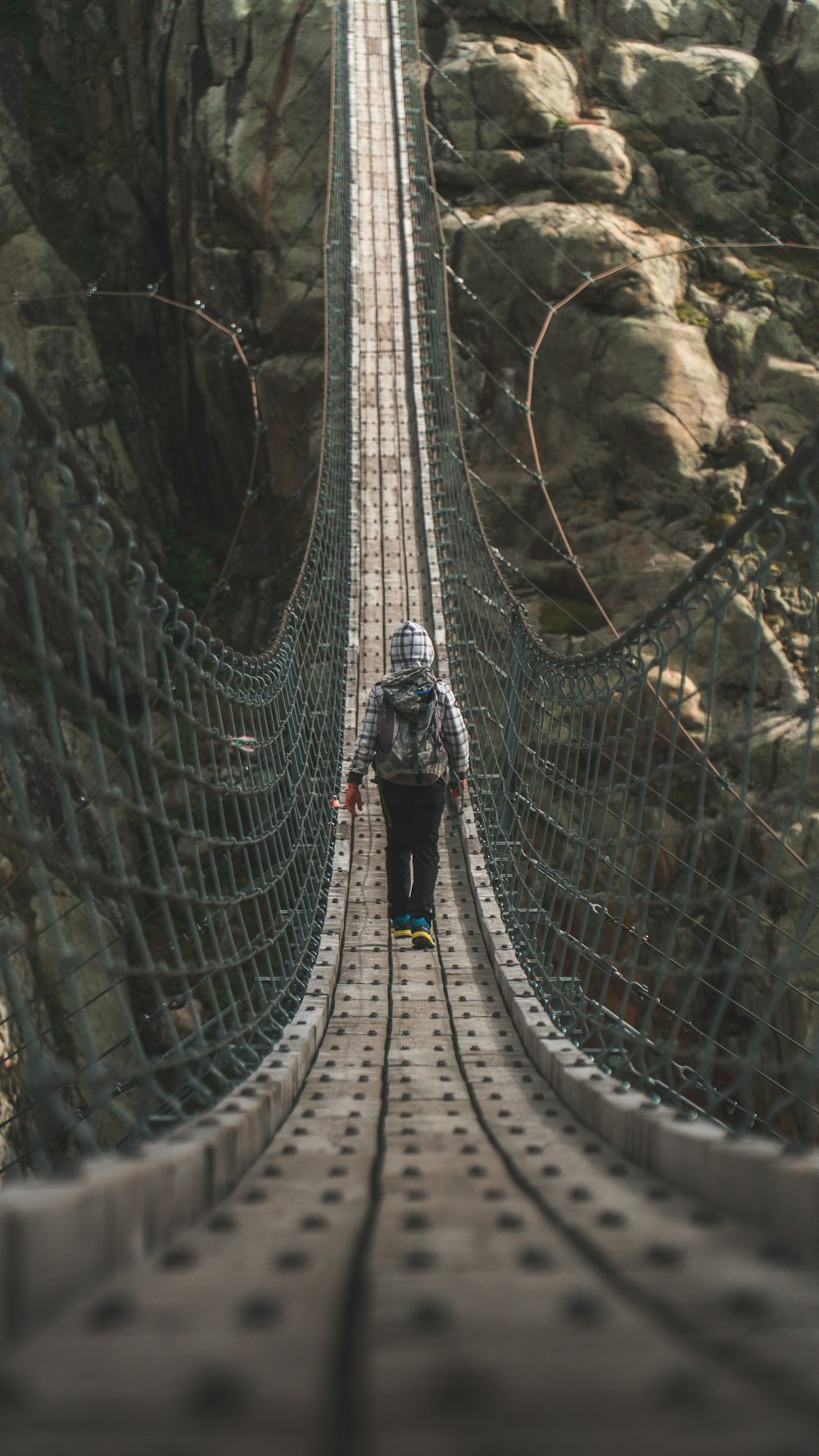 man crossing hanging bridge