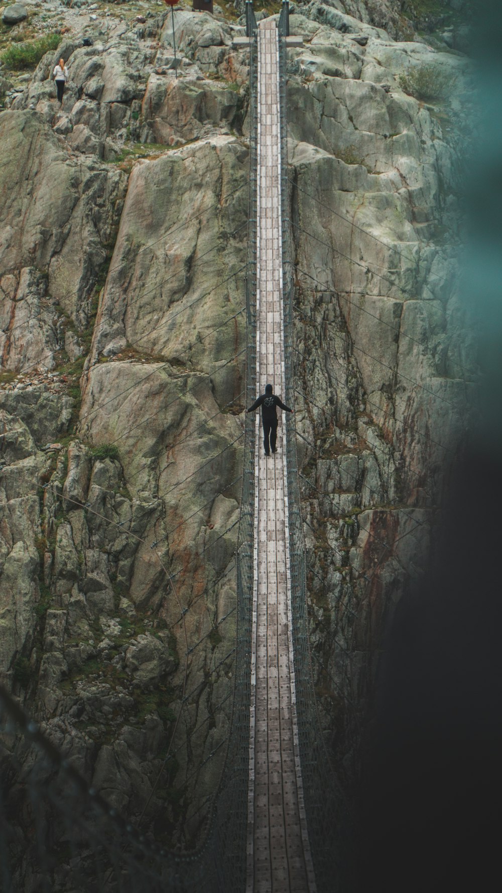 person crossing hanging bridge