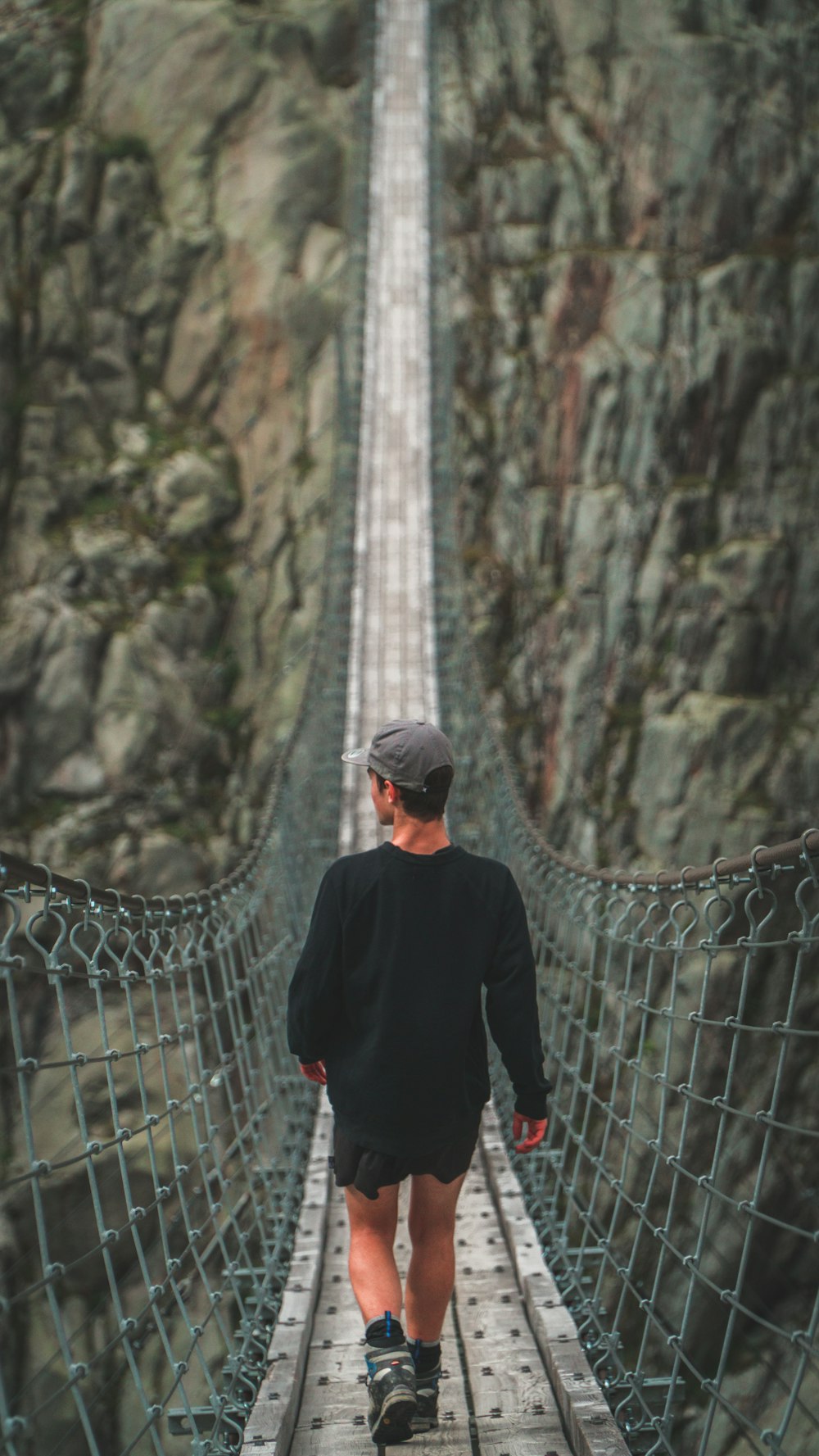 man walking on hanging bridge during daytime