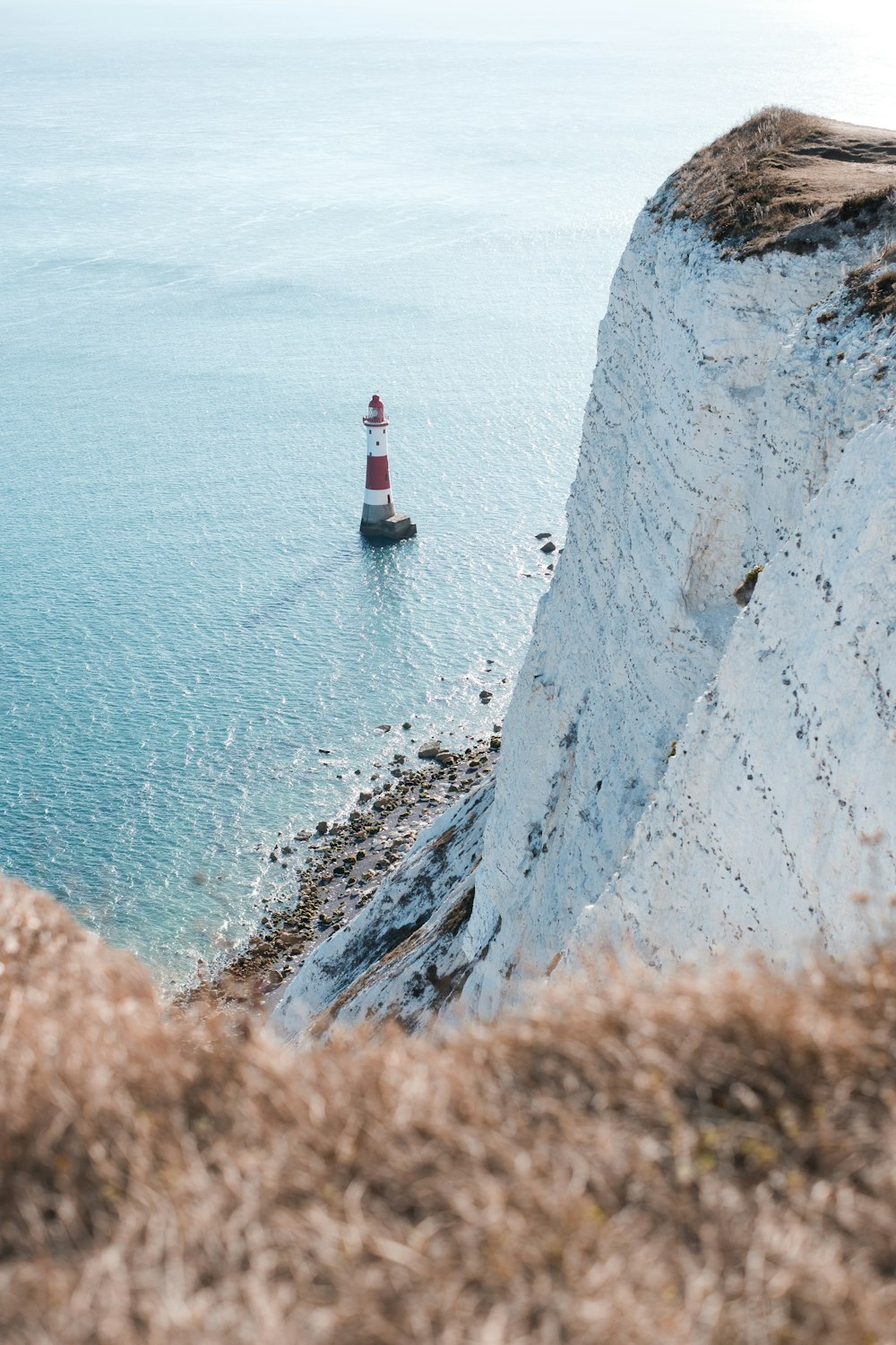 lighthouse in body of water near mountain island during day