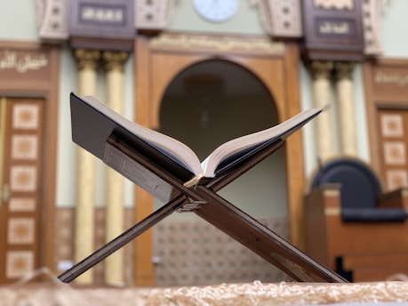 A serene study corner with an open Islamic book and a traditional wooden pen holder.