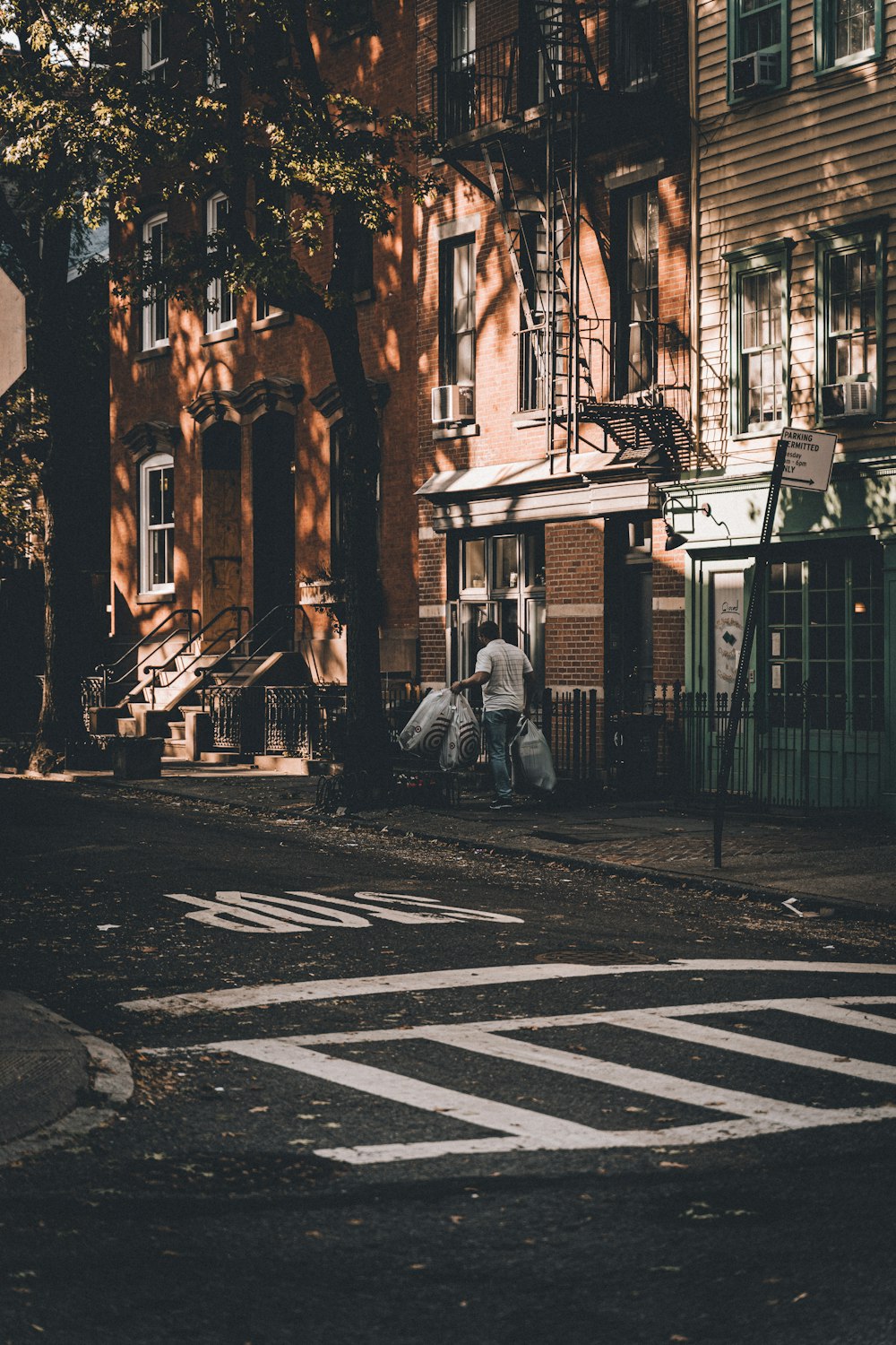 man holding white plastic bags walking near road during daytime