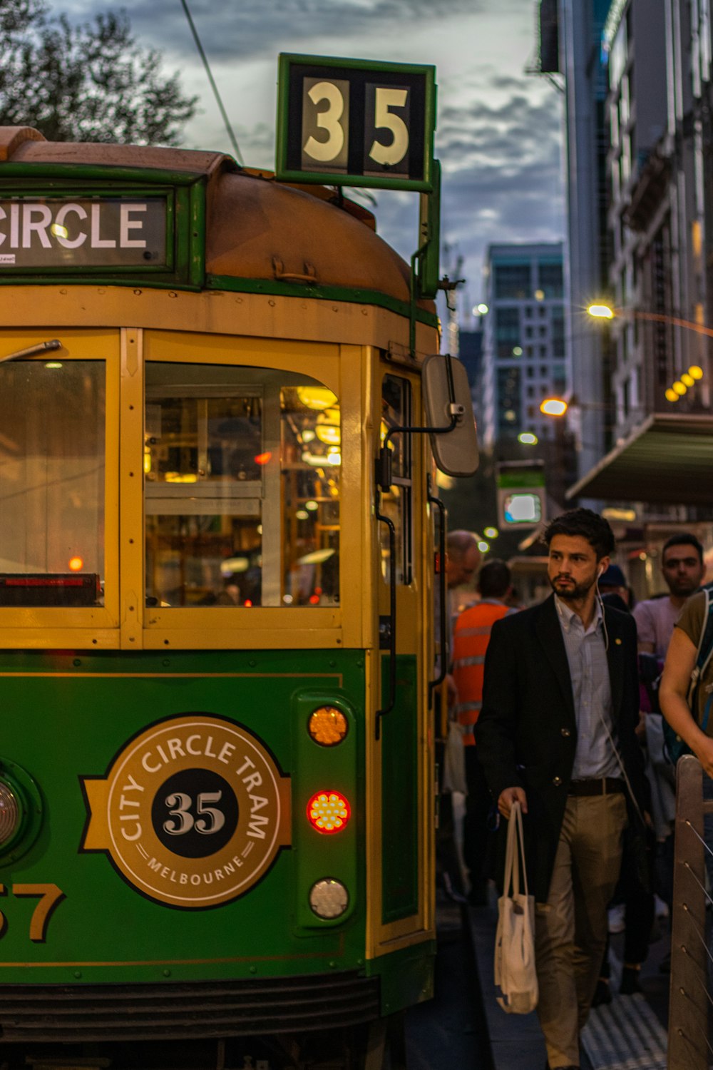 man walking near yellow and green train