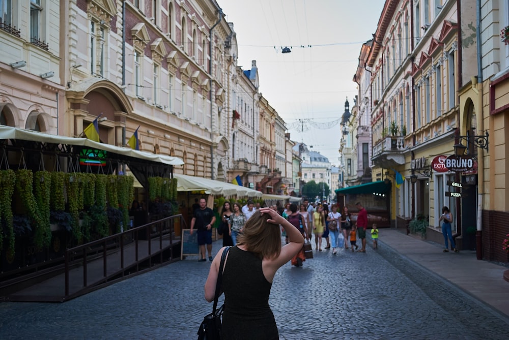 woman wearing black sleeveless dress walking on street