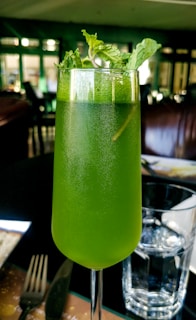 A vibrant green detox juice in a clear glass with fresh mint leaves on top