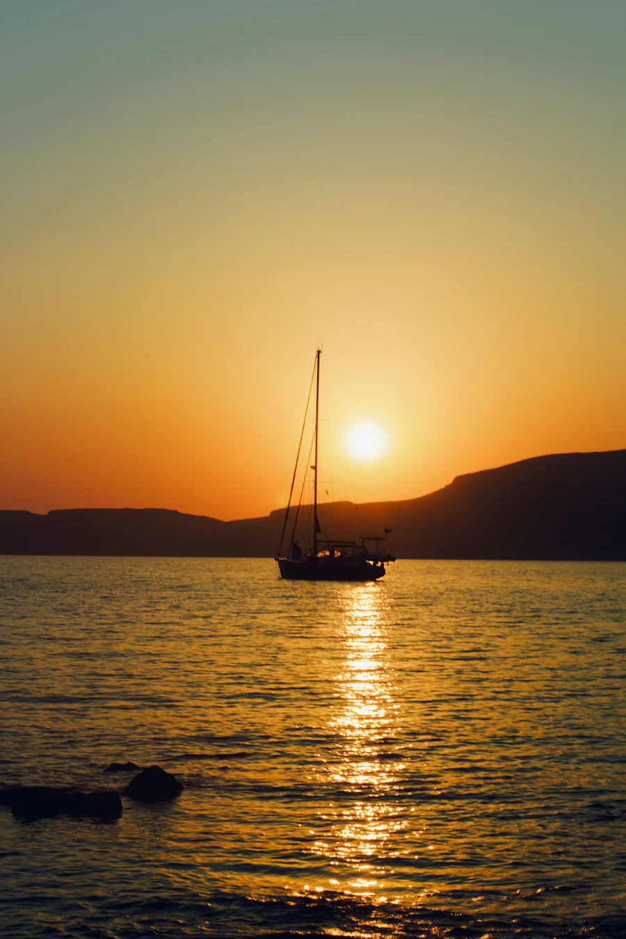 Silhouette of a sailboat on the water at sunset