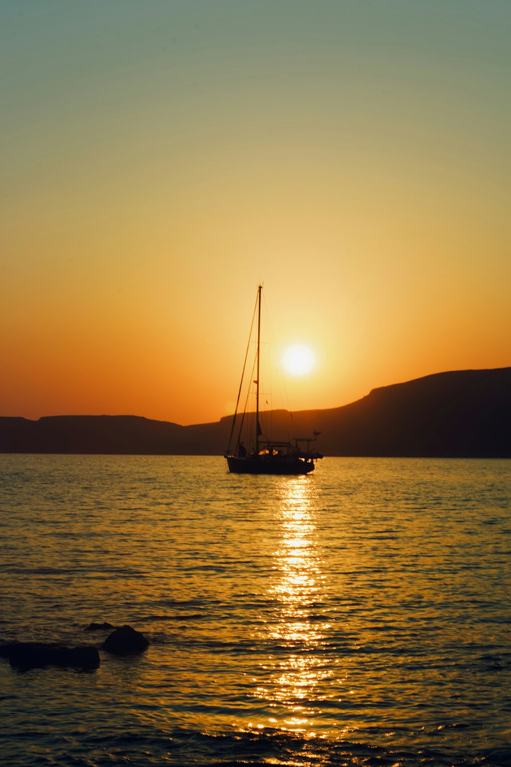 silhouette of sailboat on sea water during sunrise