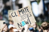 people gathered outside buildings holding Climate Justice Now signage