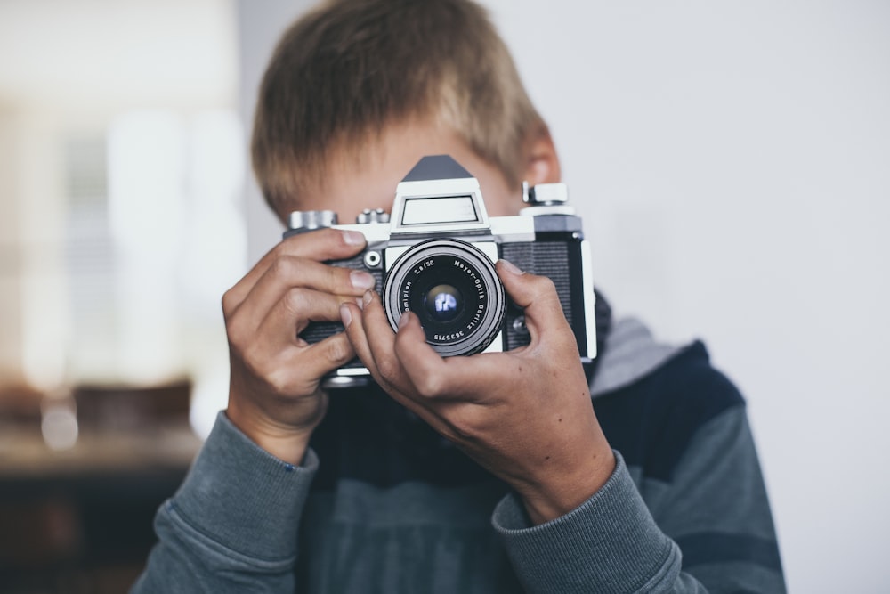 boy holding gray camera