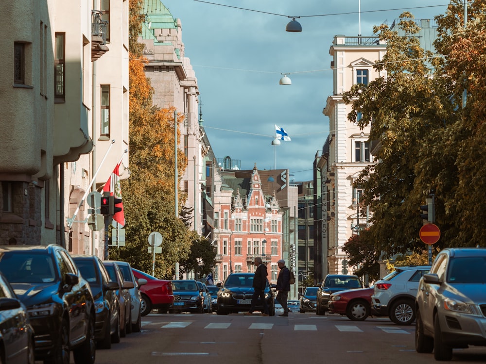 two person walking across street near parked cars